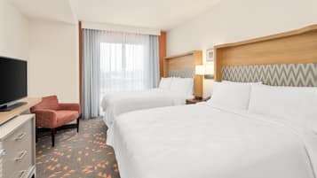 A hotel room with two beds, a TV, a desk, and a chair.