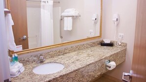A bathroom with a granite countertop, a sink, a mirror, a towel rack, a hair dryer, and a toilet paper holder. - Holiday Inn Express & Suites Pierre-fort Pierre (Fort Pierre)