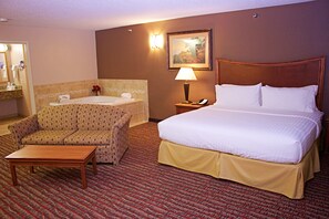 Una camera d'albergo con un letto, una sedia, un tavolino, un bagno con una vasca e un comodino con una lampada.