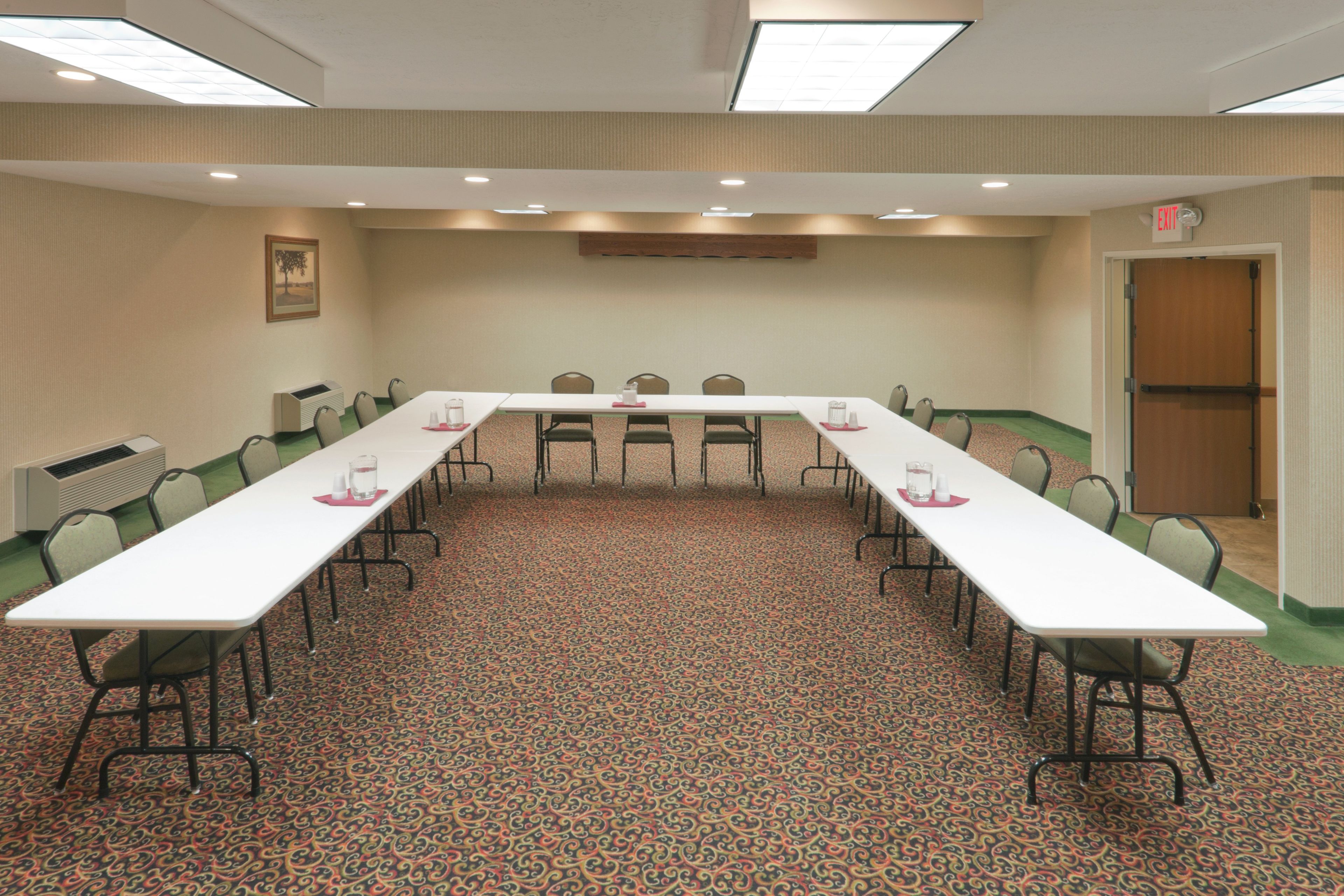 Sala de conferências com uma mesa comprida, cadeiras e um tapete estampado.