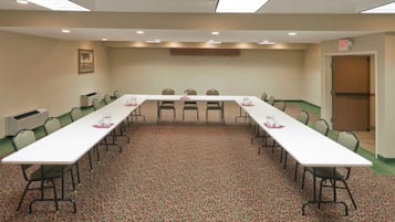 Sala de conferências com uma mesa comprida, cadeiras e um tapete estampado.
