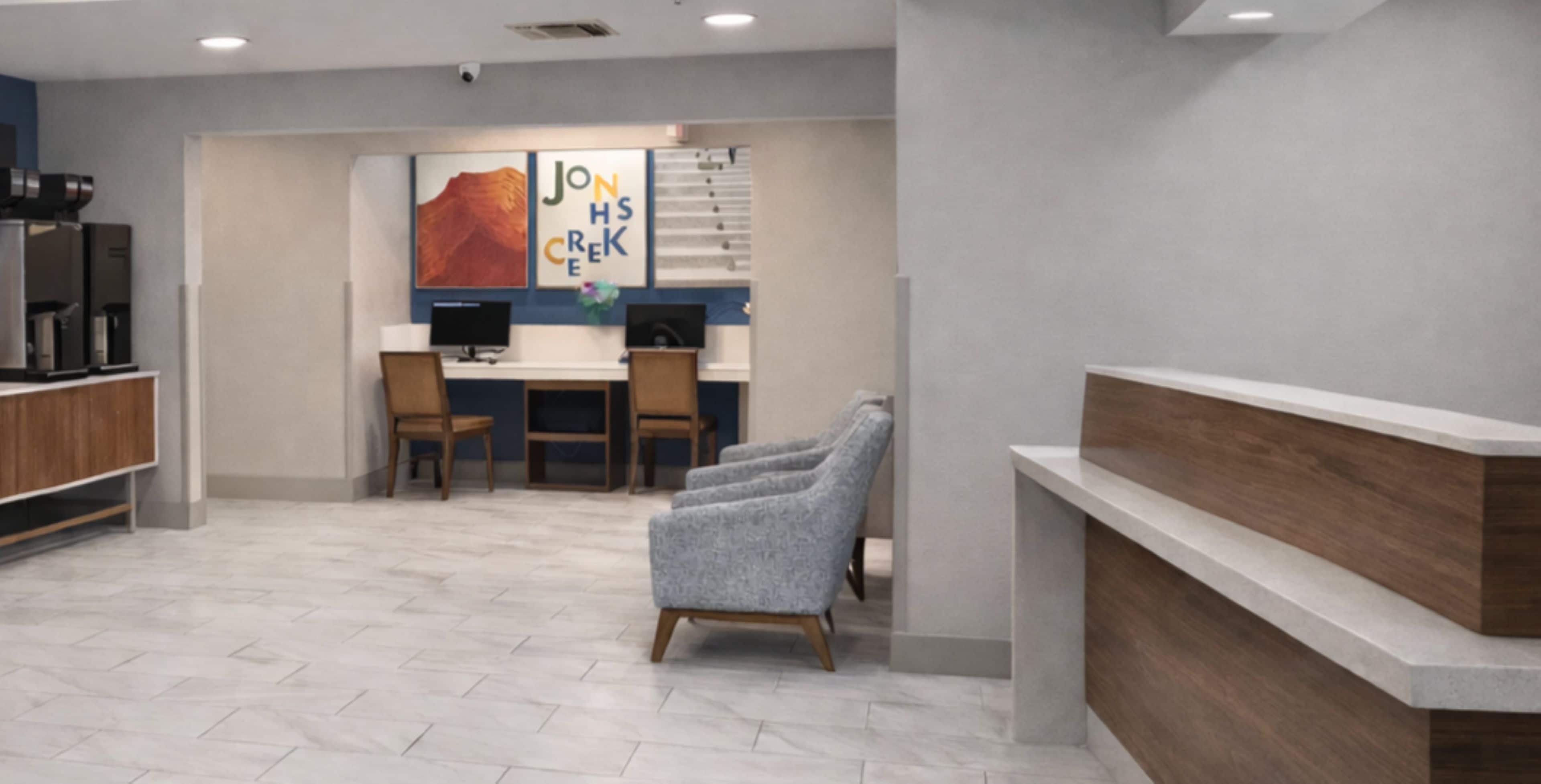A reception area with a counter, chairs, and a desk with computers.