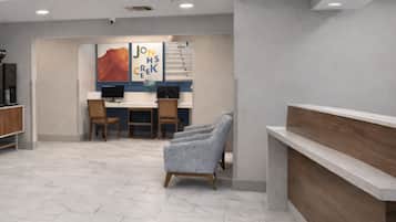 A reception area with a counter, chairs, and a desk with computers.