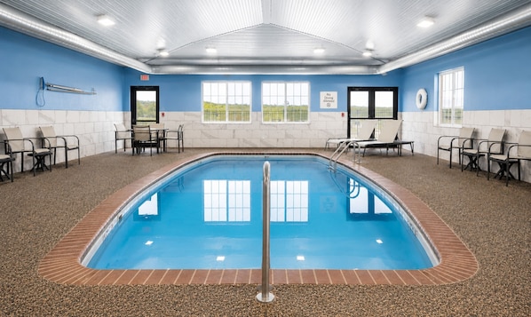 An indoor swimming pool with a tiled floor, a metal pool ladder, and chairs around the pool. - Holiday Inn Express & Suites Pierre-fort Pierre (Fort Pierre)