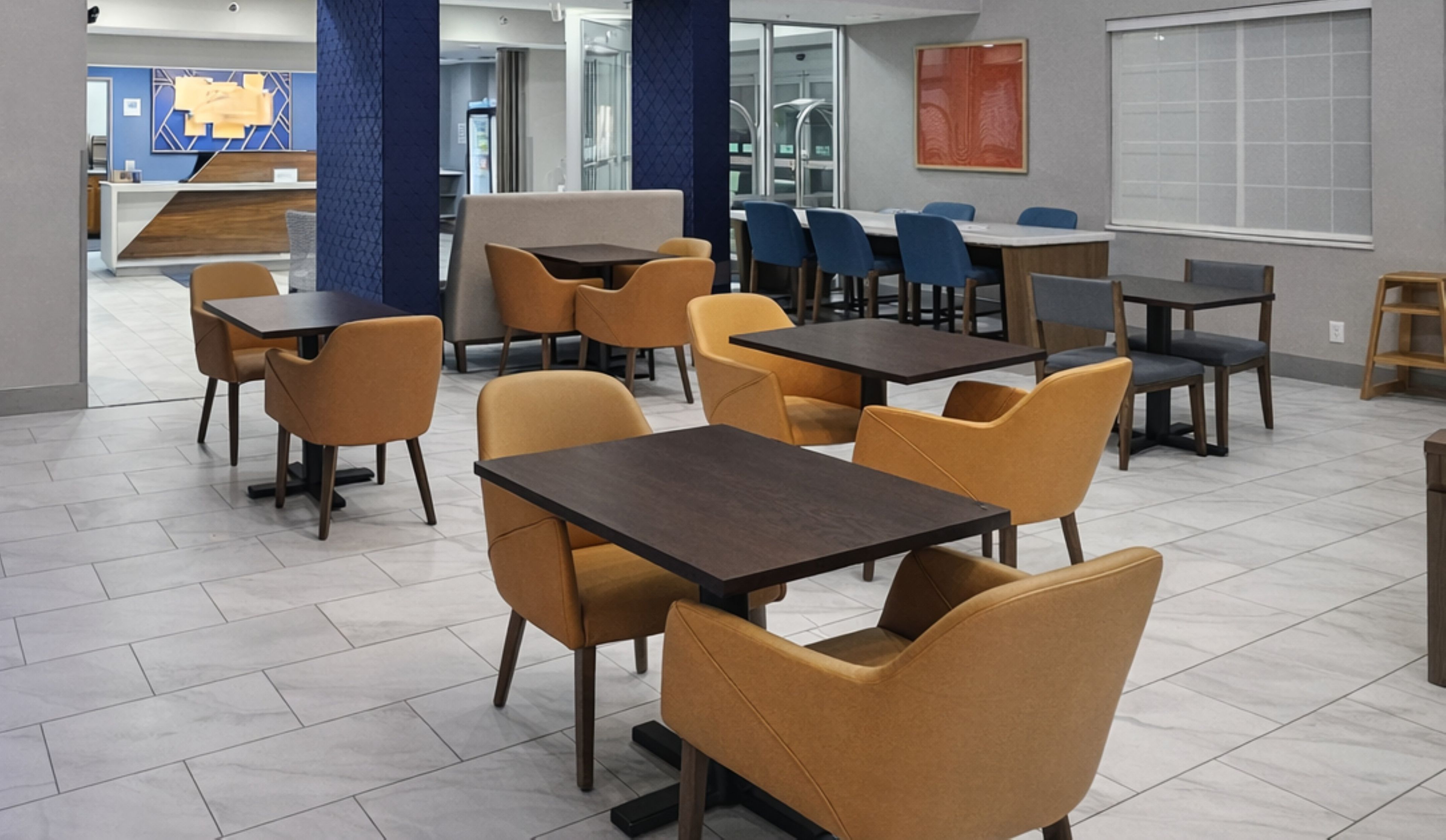 A modern dining area with tables and chairs, a reception desk, and a large window.