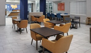 A modern dining area with tables and chairs, a reception desk, and a large window. - Holiday Inn Express & Suites Pierre-fort Pierre (Fort Pierre)