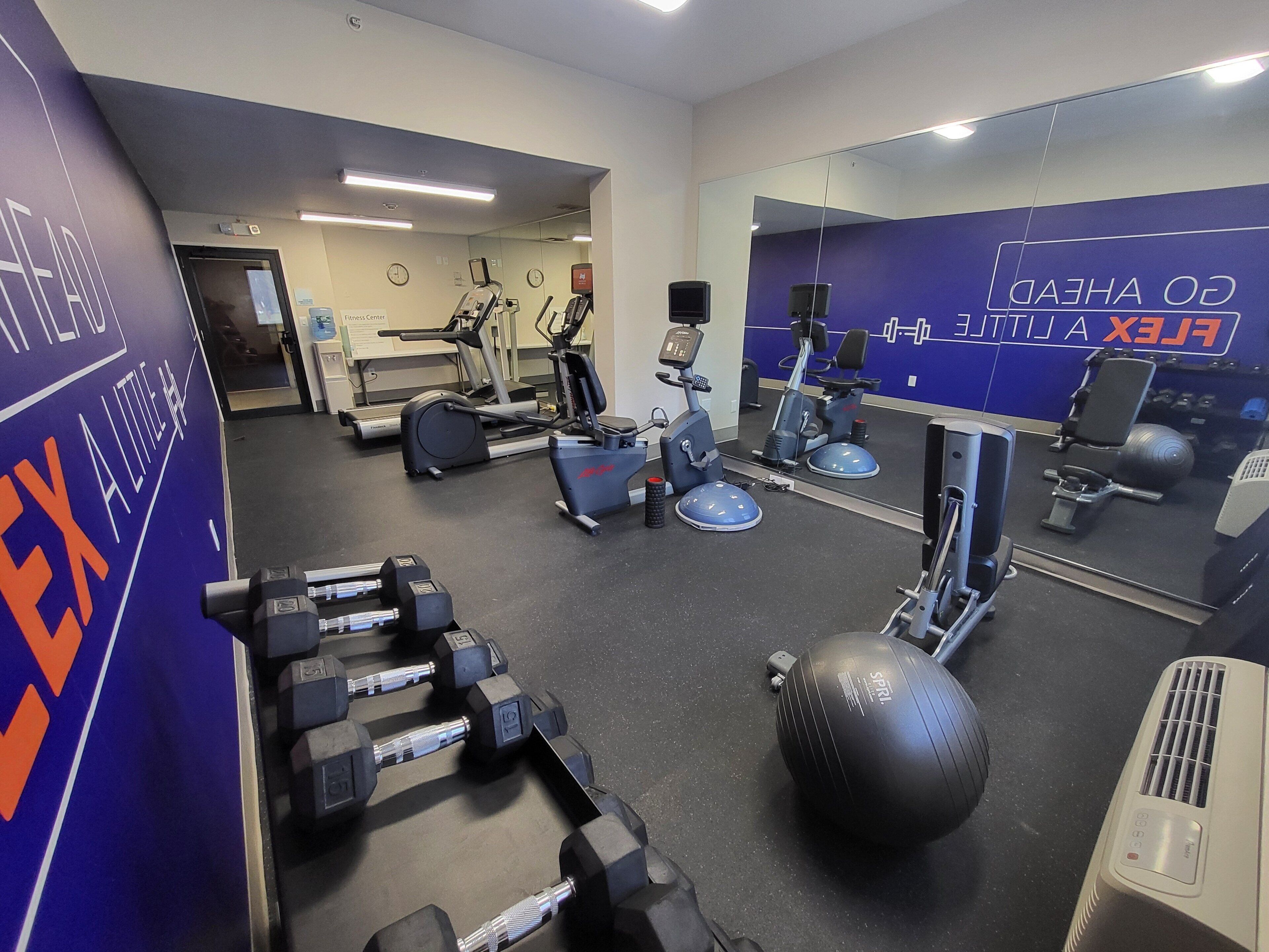 Un gimnasio con equipo de ejercicio, un espejo y una pared con texto.