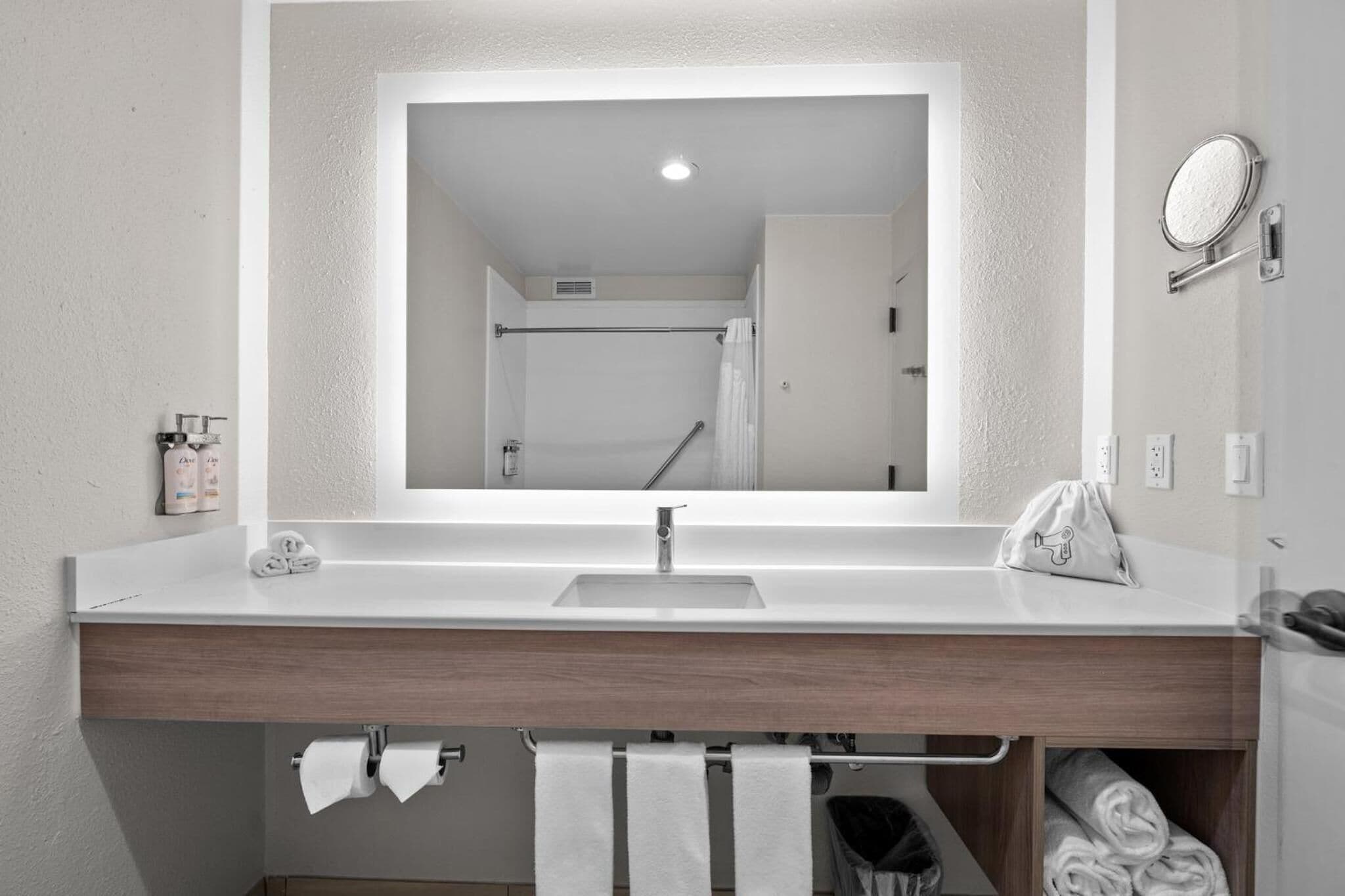 A modern bathroom with a large mirror, a sink, and a towel rack.