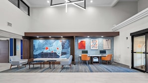 Eine moderne Lobby mit Sitzgelegenheiten, einem Empfangstisch und einem großen, abstrakten Wandbild.