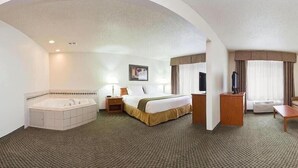 Habitació d'hotel amb un llit gran, un bany independent amb banyera, un escriptori, una cadira i una televisió.
