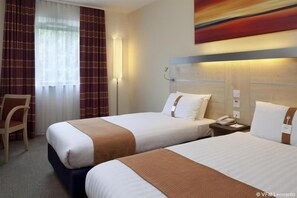 A hotel room with two beds, a chair, a bedside table with a phone, and a painting on the wall. - Holiday Inn Express Birmingham - Walsall (Walsall)