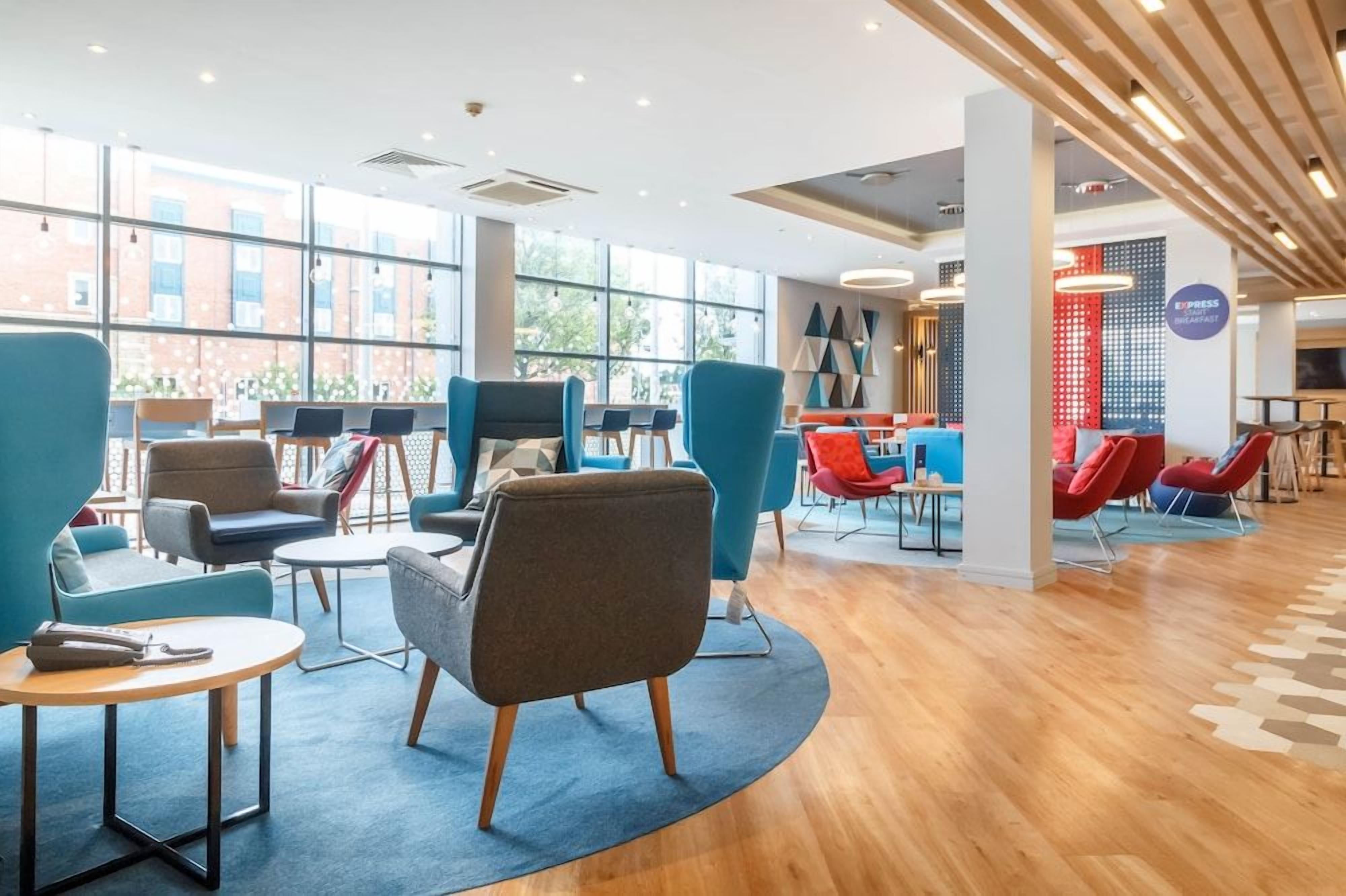 A modern lounge area with seating arrangements, a coffee bar, and large windows providing natural light.
