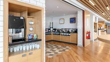 A modern kitchen with wooden cabinets, a coffee machine, and a variety of kitchenware.