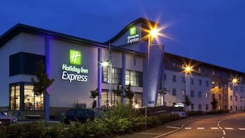 Un hotel Holiday Inn Express con una fachada moderna, amplias ventanas y una entrada bien iluminada.
