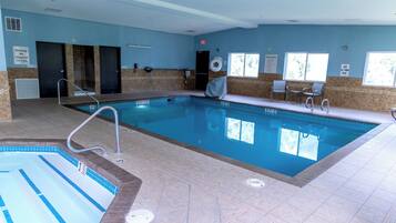 A swimming pool with a diving board, lifeguard on duty sign, and pool rules sign.