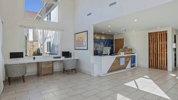 A modern office space with a reception desk, two computer workstations, and a large window.