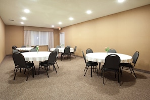 A conference room with round tables, black chairs, and beige carpet. - Holiday Inn Express & Suites Torrington (Torrington)