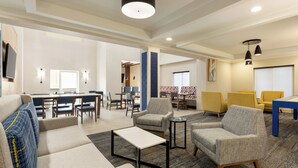 A spacious hotel lobby with a seating area, a small table, and a dining area.