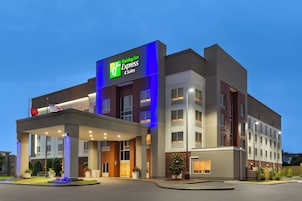 A Holiday Inn Express & Suites building with a modern design, featuring a prominent sign, a covered entrance, and a landscaped front yard.