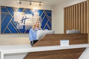A reception desk with a modern design, a sign for Holiday Inn Express, and a computer monitor.
