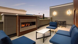 An outdoor patio area with a built-in fireplace, blue seating, and a dining table.