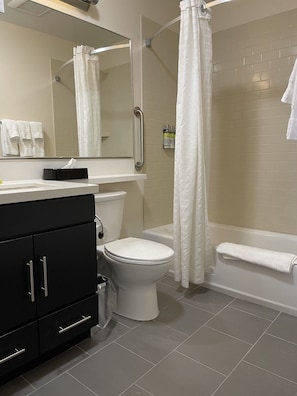 Un baño con inodoro, lavabo, espejo, ducha y bañera.