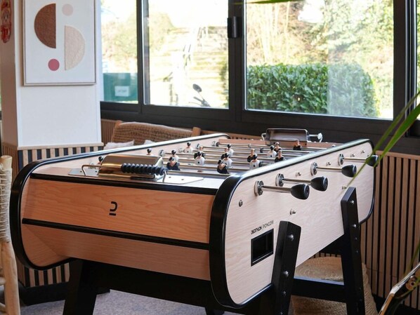 A foosball table in a room with a window, a radiator, and a framed picture on the wall. - Ibis Caen Porte d Angleterre (Herouville-Saint-Clair)
