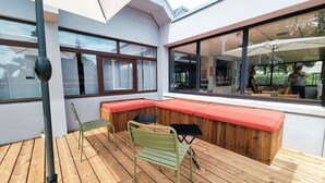 A modern outdoor seating area with wooden flooring, a green metal chair, and a black table. - Ibis Caen Porte d Angleterre (Herouville-Saint-Clair)