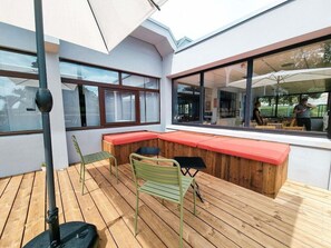 Ein moderner Außenbereich mit Holzboden, einem grünen Metallstuhl und einem schwarzen Tisch.