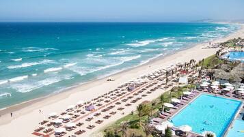 A beach resort with a pool, sun loungers, and a view of the ocean.