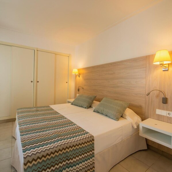 A hotel room with a bed, a nightstand, a lamp, and a wardrobe. - Hotel La Santa Maria (Sant Llorenc des Cardassar)