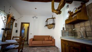 Un accogliente soggiorno con divano, tavolo da pranzo in legno, sedie e lampadario.