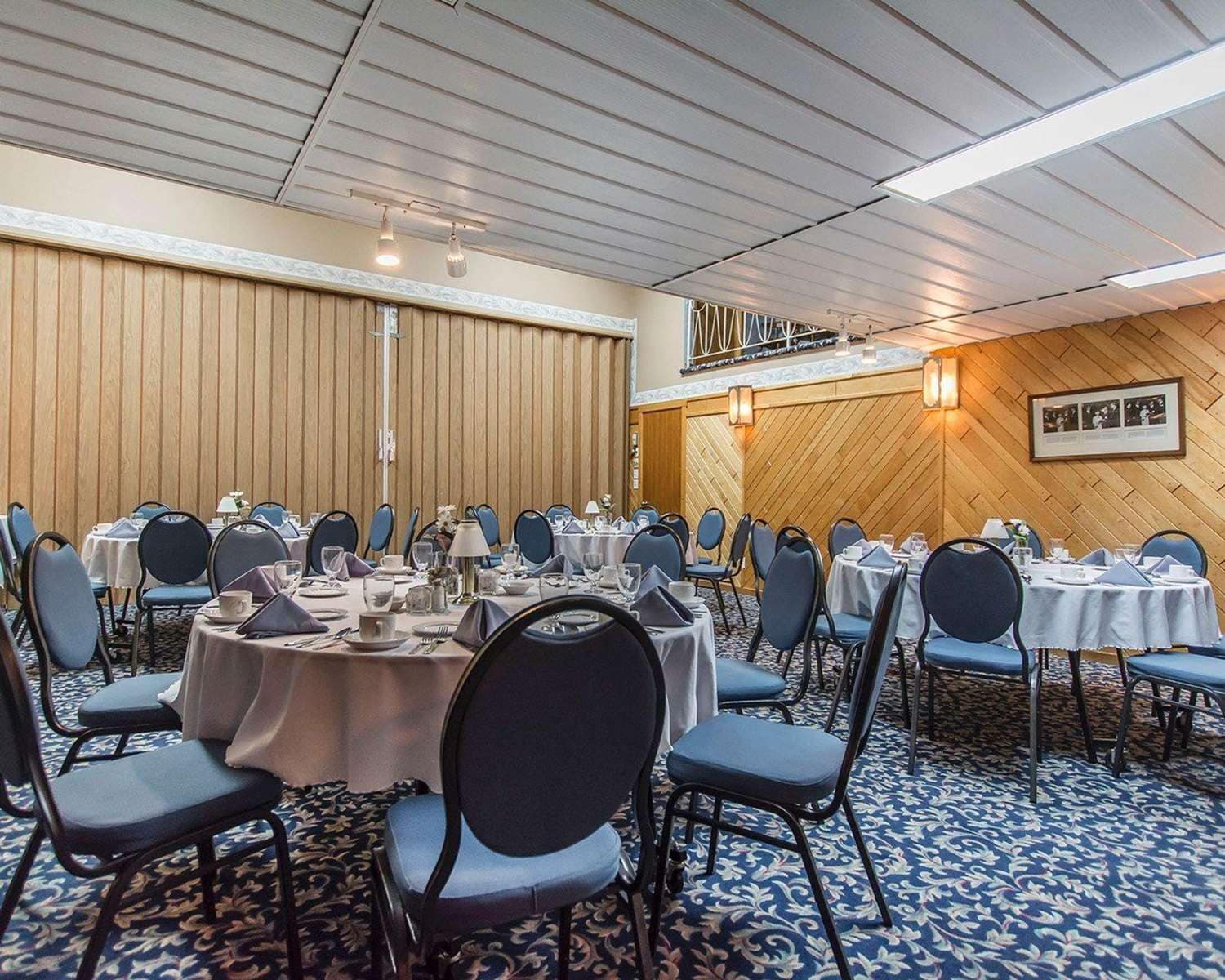 A conference room with round tables, chairs, and a patterned carpet.
