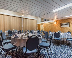 A conference room with round tables, chairs, and a patterned carpet. - Rodeway Inn Grand Falls (St. Andre)