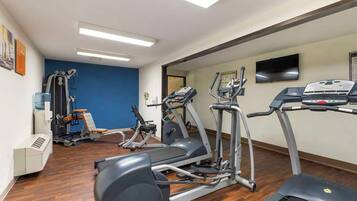 A gym with cardio machines, weight machines, and a water cooler.