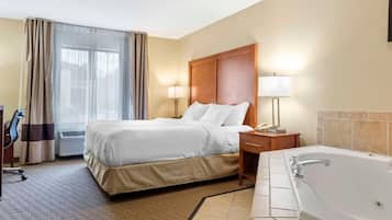 A hotel room with a bed, bedside table, lamp, and a separate bathroom with a bathtub.