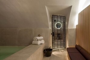 A spa room with a bathtub, a bench, a towel rack, and a decorative door. - Cour des Vosges (Paris)