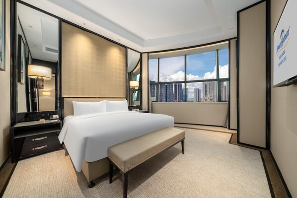 A hotel room with a large bed, a bench, a desk, a mirror, and a view of the cityscape through a large window. - Howard Johnson Plaza By Wyndham Ningbo (Ningbo)