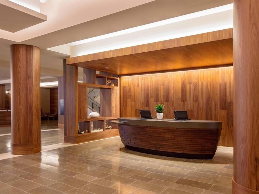 A reception area with a wooden reception desk, a potted plant, and a modern interior design.