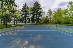 A tennis court with a net, surrounded by trees and a bench. - Hyatt Regency Lake Washington (Renton)