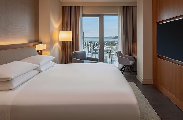 A hotel room with a large bed, two armchairs, a desk, and a TV. - Hyatt Regency Lake Washington (Renton)