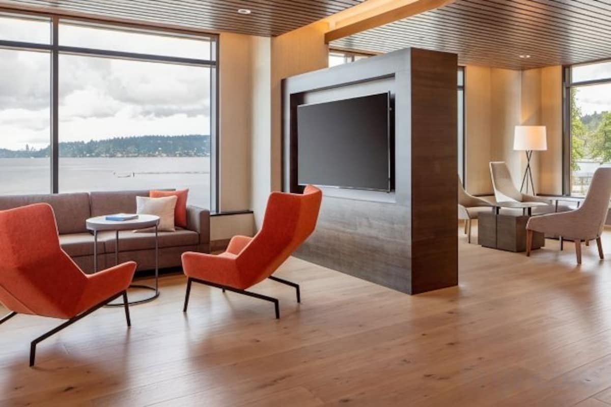 A modern interior with a sofa, two armchairs, a coffee table, and a TV screen.