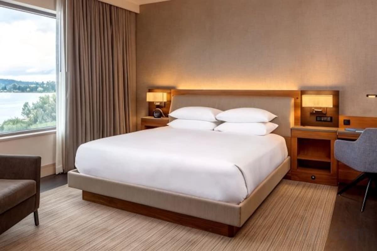 A hotel room with a large bed, bedside tables, a desk, and a view of the outdoors.