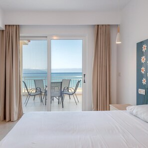 A hotel room with a bed, a balcony with chairs, and a view of the sea. - Marina Bay Hotel Aparthotel (Kefalonia)