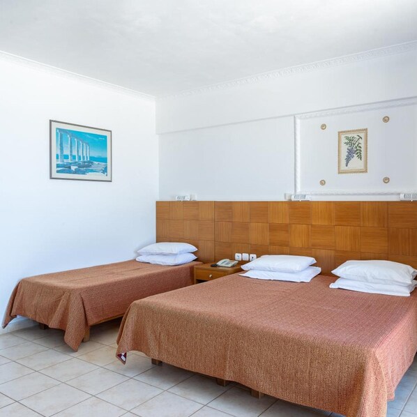 A hotel room with two beds, a wooden headboard, a painting of a bridge, and a wall-mounted plant. - Marina Bay Hotel Aparthotel (Kefalonia)
