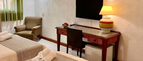 Ein Hotelzimmer mit zwei Betten, einem Schreibtisch, einem Stuhl, einem Fernseher und einer Lampe.