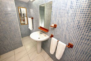 A bathroom with a white sink, mirror, and tiled walls.