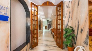 Un pasillo con suelo de mármol y puertas de madera que dan a una zona de estar.