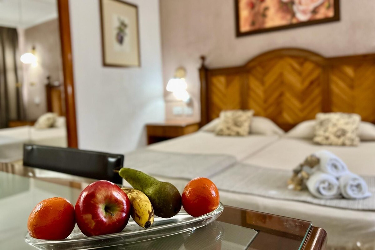Ein Hotelzimmer mit einem Bett, einem Nachttisch mit Handtüchern, einer Obstschale und einem Bild an der Wand.