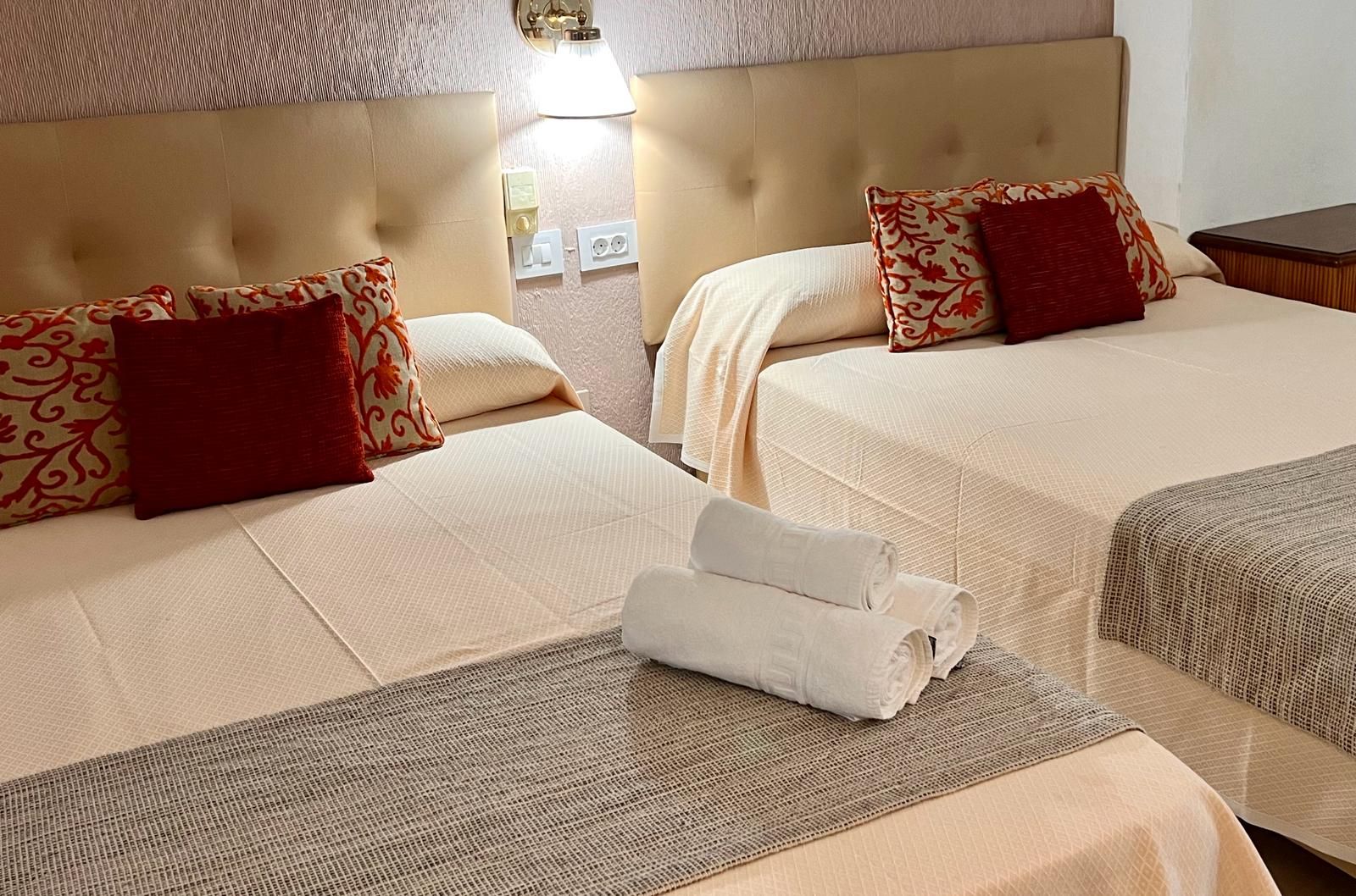 Une chambre d’hôtel avec deux lits, chacun doté d’une tête de lit, et une petite table avec des serviettes.